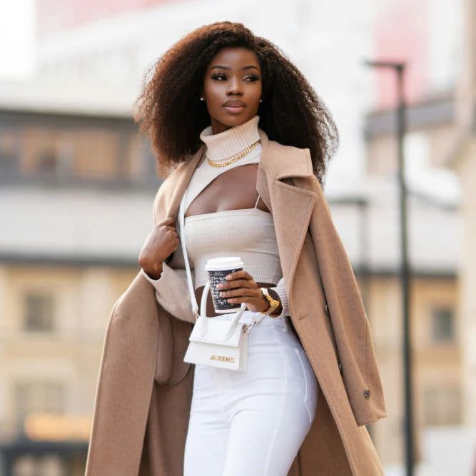 Woman in a beige coat holding a coffee cup outdoors